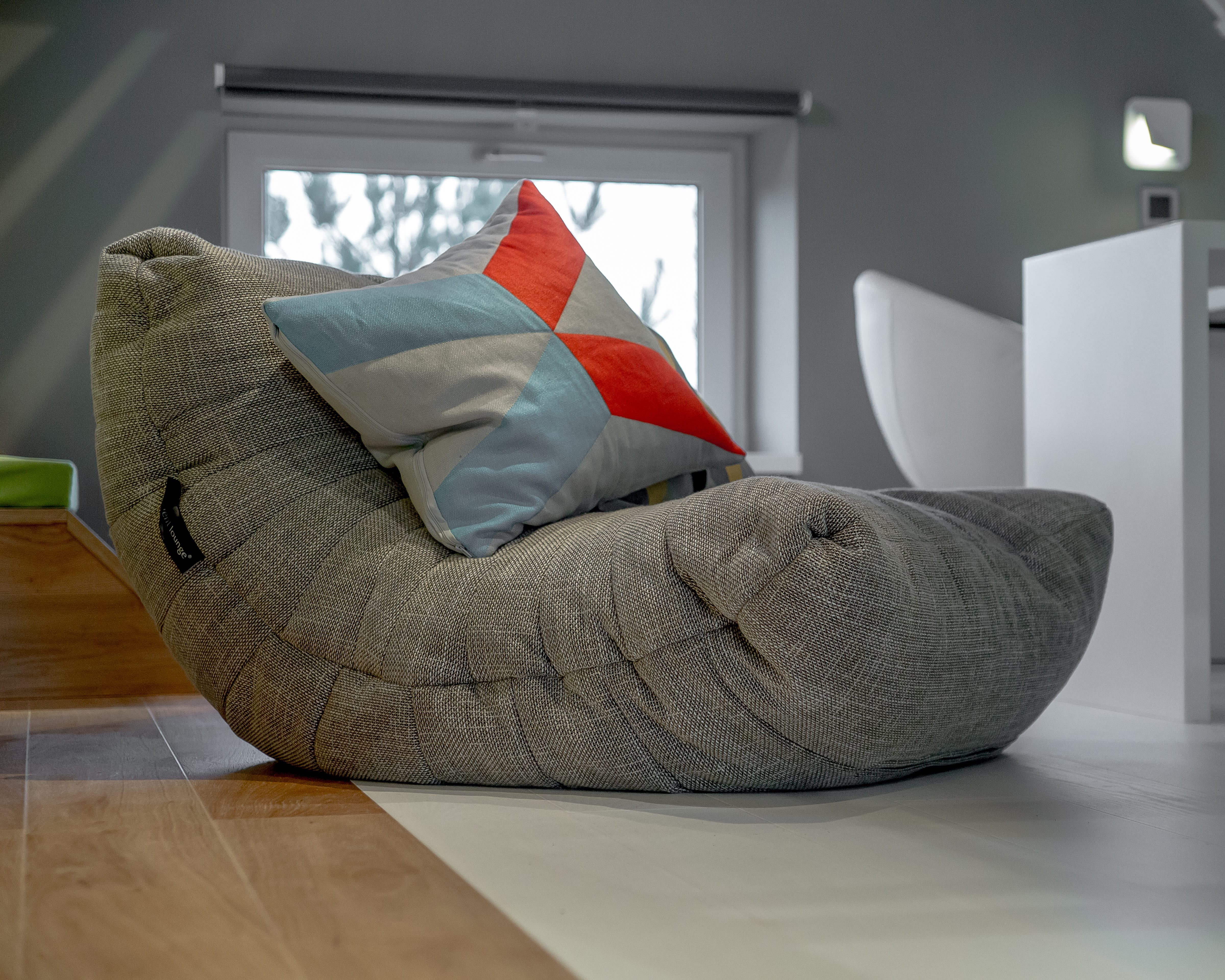 Beige Acoustic Sofa bean bag with a colourful cushion in a modern attic.