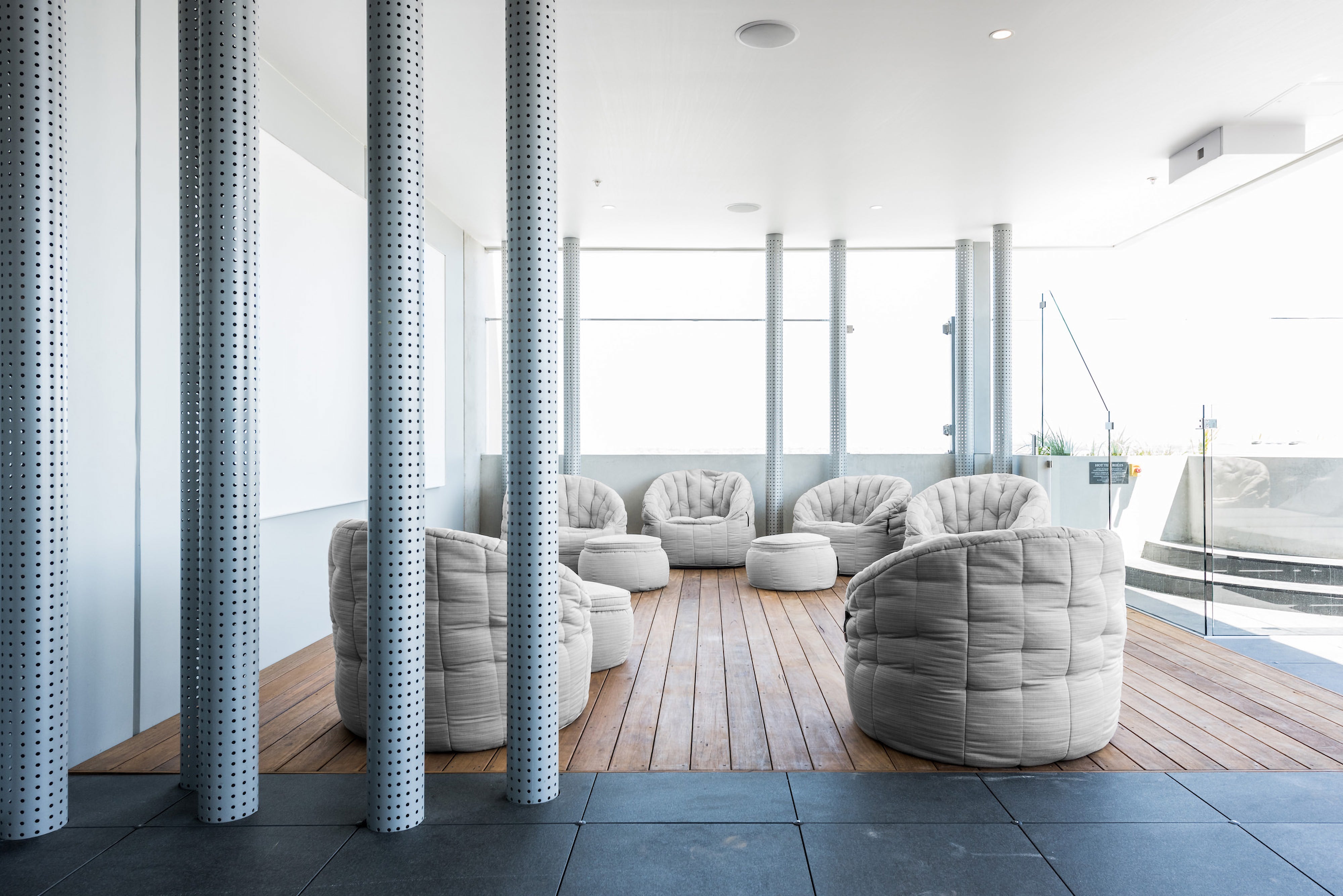 Modern airy light-filled rooftop deck with grey Butterfly Sofa and Wing Ottoman bean bags.
